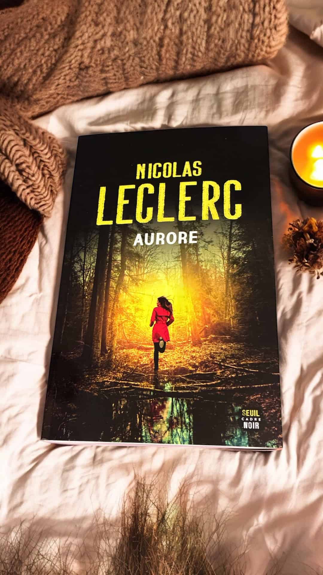Livre Aurore de Nicolas Leclerc posé sur un plaid ivoire avec une tasse de thé, roman sombre et addictif